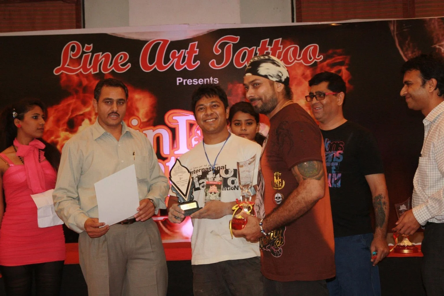 Tattoo convention award ceremony, India Tattoo artists on stage holding trophies and certificates at a Line Art Tattoo convention award ceremony in India.